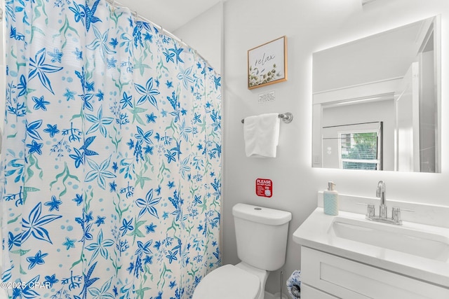 bathroom featuring curtained shower, visible vents, vanity, and toilet