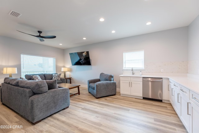 living room with a wealth of natural light, light hardwood / wood-style flooring, ceiling fan, and sink