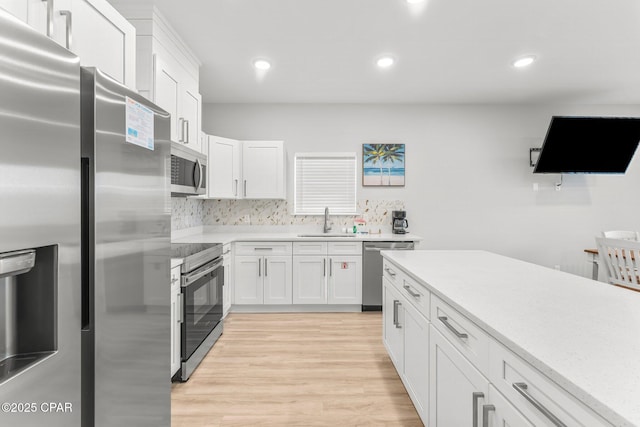 kitchen featuring light countertops, light wood-style flooring, appliances with stainless steel finishes, white cabinets, and a sink