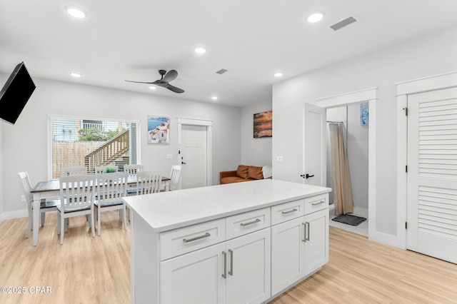 7026 Thomas Dr Unit A & B, Panama City Beach, FL 32408 - kitchen featuring light wood-style flooring, light countertops, a ceiling fan, a center island, and white cabinetry