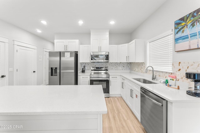 kitchen featuring light countertops, appliances with stainless steel finishes, a sink, and white cabinets