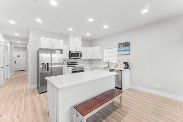 kitchen featuring light wood-type flooring, white cabinetry, appliances with stainless steel finishes, and light countertops