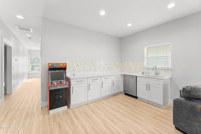 kitchen with white cabinets, light countertops, a sink, and stainless steel dishwasher