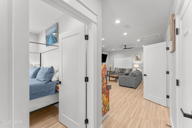 corridor with visible vents, light wood-type flooring, attic access, and recessed lighting