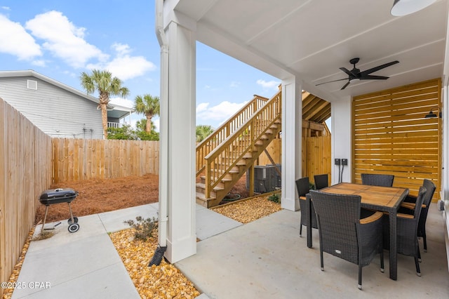 view of patio / terrace with ceiling fan, a fenced backyard, central AC, stairs, and outdoor dining space