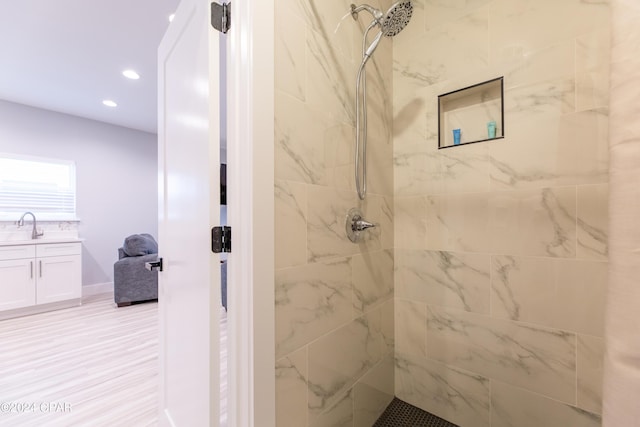 bathroom with vanity, a tile shower, and wood-type flooring