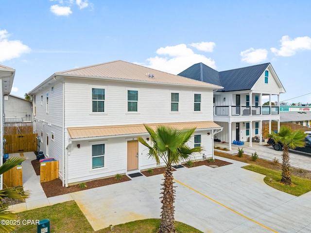 view of front of property with a balcony, fence, metal roof, and concrete driveway