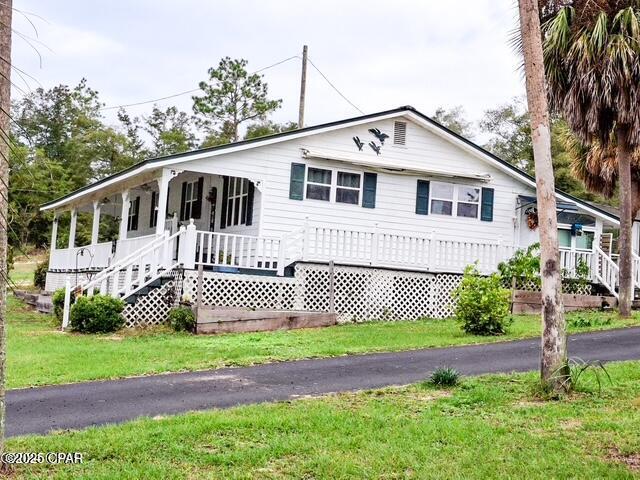 view of front of home with covered porch, aphalt driveway, and a front lawn