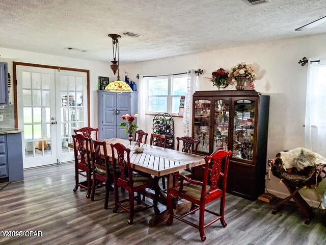 dining space featuring dark wood-style floors, french doors, a textured ceiling, and visible vents