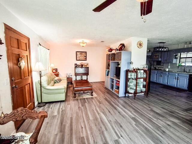 living area featuring a textured ceiling, wood finished floors, and a ceiling fan