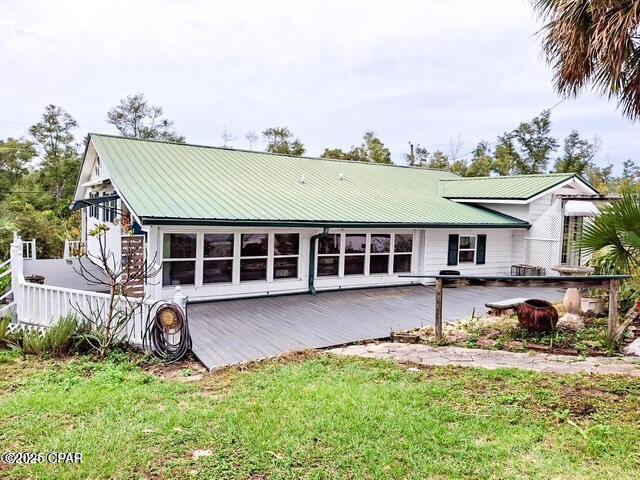 back of house featuring metal roof and a lawn