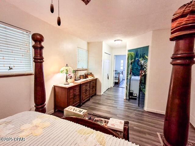 bedroom featuring dark wood-style floors, multiple windows, and baseboards