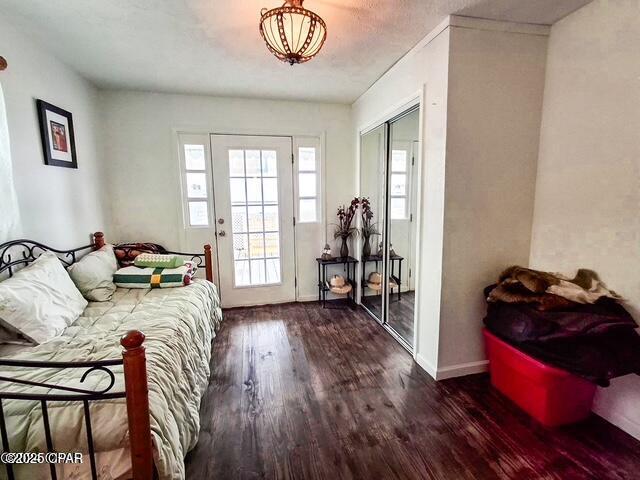 bedroom featuring baseboards, dark wood-type flooring, a closet, and access to exterior