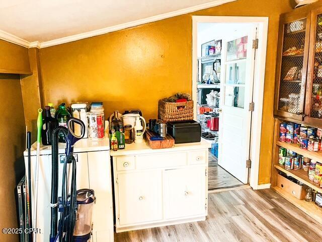 kitchen featuring light countertops, light wood-style flooring, ornamental molding, glass insert cabinets, and white cabinets