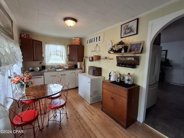 kitchen with white oven, light hardwood / wood-style floors, fridge, and sink