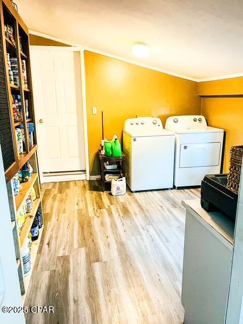 laundry area featuring laundry area, washer and dryer, light wood-style floors, baseboard heating, and crown molding