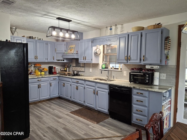 kitchen with black appliances, sink, hanging light fixtures, decorative backsplash, and light wood-type flooring