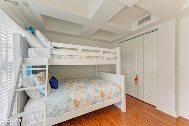 bedroom featuring baseboards, visible vents, coffered ceiling, and wood finished floors