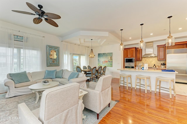 living room featuring baseboards, recessed lighting, a ceiling fan, and light wood-style floors