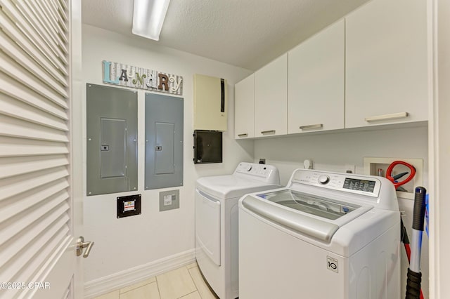 washroom featuring washer and dryer, electric panel, cabinet space, and a textured ceiling