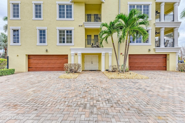 multi unit property featuring driveway, an attached garage, and stucco siding