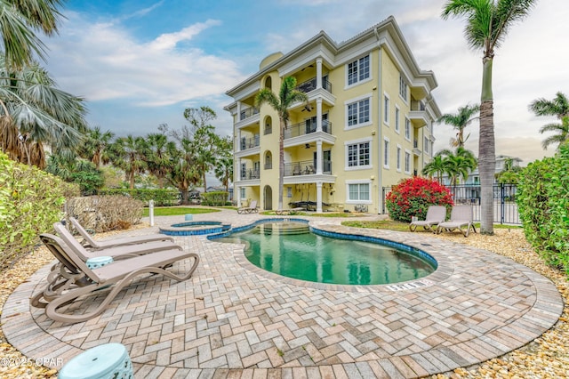 view of pool featuring a pool with connected hot tub, a patio area, and fence