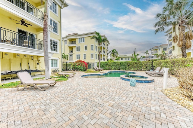 view of pool featuring a pool with connected hot tub, a patio area, a residential view, and a ceiling fan