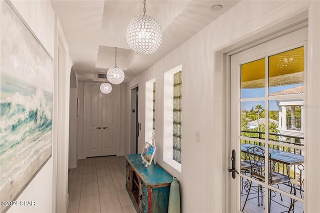 hallway with light tile patterned floors and an inviting chandelier