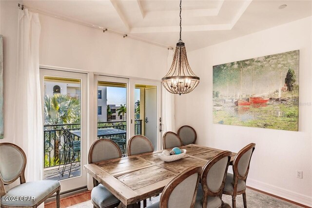 dining room featuring wood-type flooring, a raised ceiling, and a notable chandelier