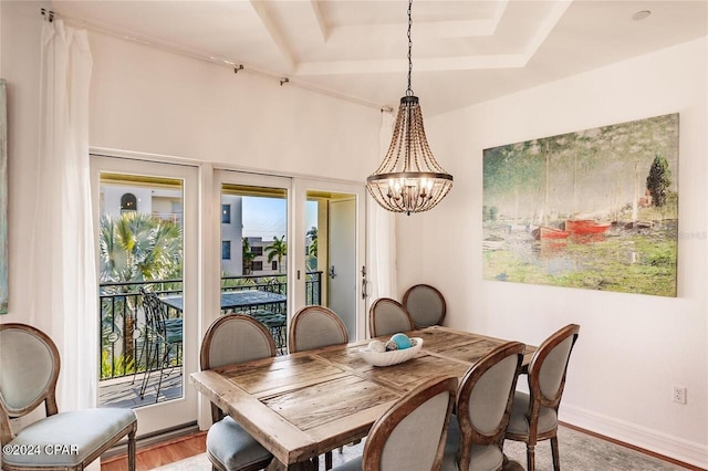 dining room featuring a chandelier, a tray ceiling, light wood-style flooring, and baseboards