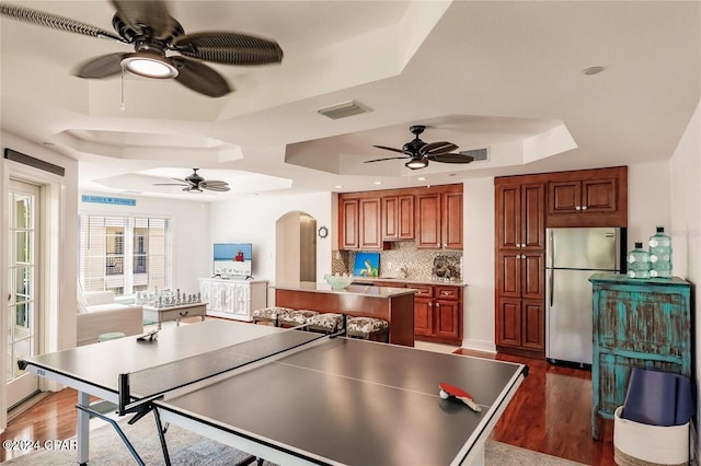 recreation room featuring dark hardwood / wood-style floors, a raised ceiling, and ceiling fan