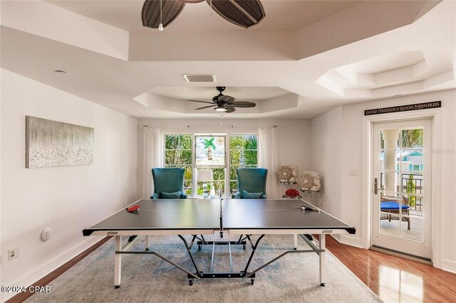 game room featuring hardwood / wood-style floors, a raised ceiling, and ceiling fan