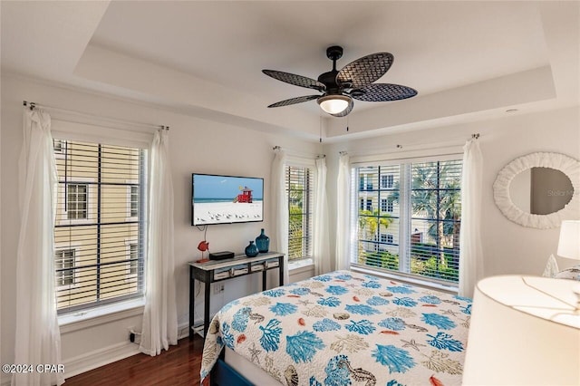 bedroom with a tray ceiling, ceiling fan, and dark wood-type flooring