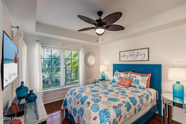 bedroom with a tray ceiling, ceiling fan, and dark hardwood / wood-style flooring