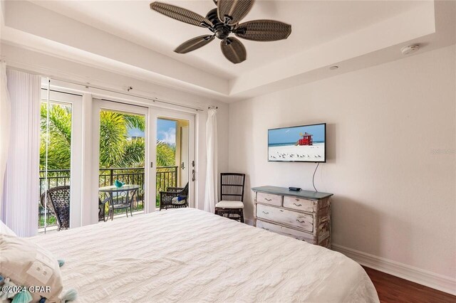 bedroom with access to outside, a raised ceiling, ceiling fan, and dark hardwood / wood-style floors