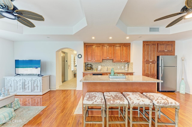 kitchen with visible vents, arched walkways, a raised ceiling, and freestanding refrigerator