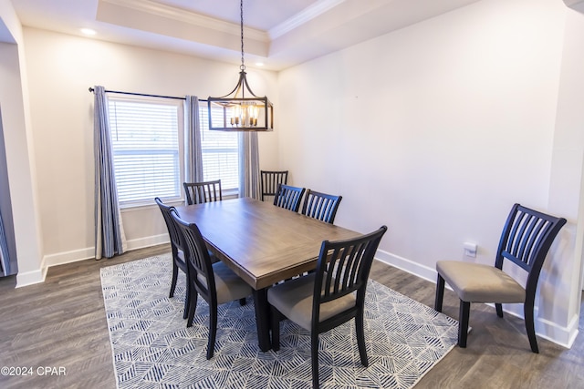 dining room with a raised ceiling, a notable chandelier, dark hardwood / wood-style flooring, and crown molding