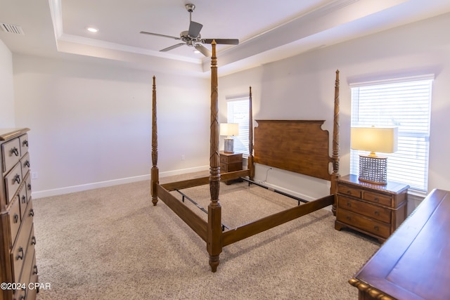 bedroom with ceiling fan, light colored carpet, ornamental molding, and a tray ceiling