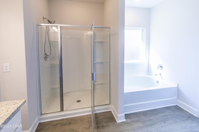 bathroom with hardwood / wood-style flooring, vanity, and plus walk in shower