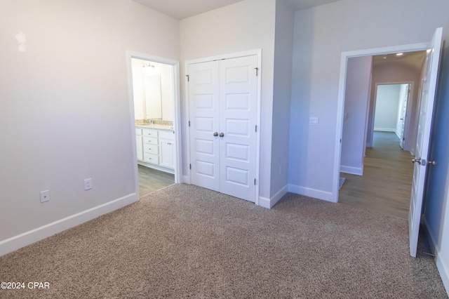 unfurnished bedroom featuring connected bathroom, light carpet, and a closet