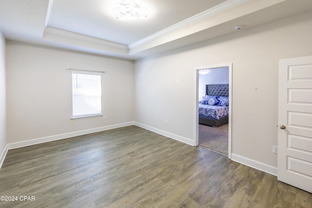 unfurnished room with dark hardwood / wood-style floors, a raised ceiling, and crown molding