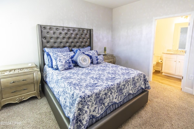 bedroom featuring sink, light carpet, and ensuite bath