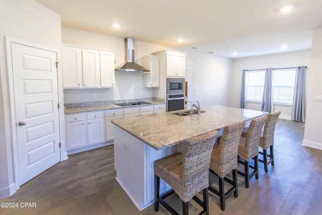 kitchen featuring an island with sink, white cabinetry, and wall chimney range hood