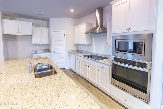 kitchen featuring sink, stainless steel appliances, wall chimney range hood, white cabinets, and light wood-type flooring