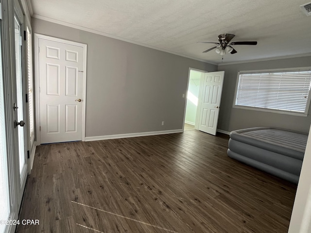 interior space featuring ceiling fan, dark hardwood / wood-style flooring, ornamental molding, and a textured ceiling