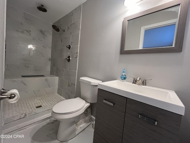 bathroom with tiled shower, vanity, and toilet