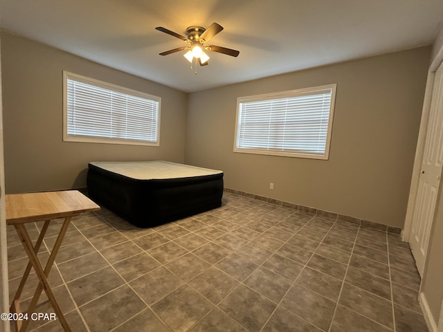 tiled bedroom with multiple windows, ceiling fan, and a closet