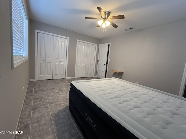 bedroom with multiple closets, ceiling fan, and tile patterned flooring