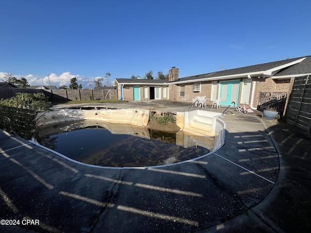 back of property featuring an empty pool and a patio area