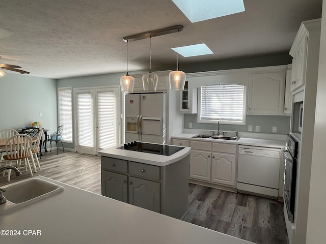 kitchen with a wealth of natural light, sink, white cabinets, and white appliances